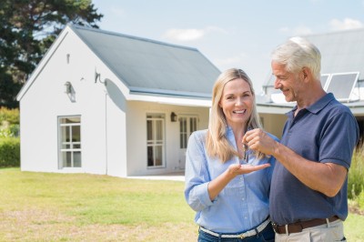 senior couple standing outside their new house with keys